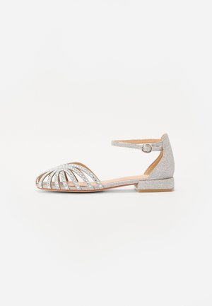Sandal aperto in argento con design a incrocio, dettagli in strass, cinturino alla caviglia e tacco basso a blocco. Parte superiore texturizzata e suola liscia.