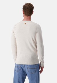 Hellbeige Sweatshirt mit Rundhalsausschnitt, gerippten Bündchen und Saum. Verfügt über ein kleines, braunes Logo-Patch am Rücken des Ausschnitts und eine glatte Textur.