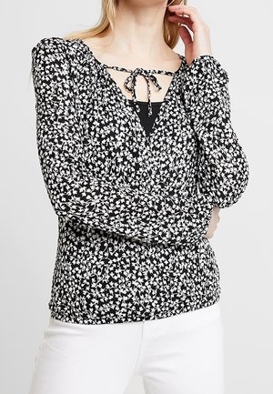 Blusa floreale in bianco e nero con maniche lunghe, scollatura a barchetta con chiusura a legaccio e dettagli arricciati in vita.