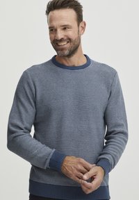 Sötétkék kötött pulóver vízszintes csíkos mintával, bordás kerek nyakkivágással és mandzsettákkal. Hosszú ujjú, puha anyagból készült.