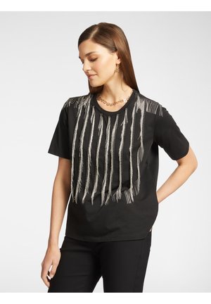 Black shirt featuring silver fringe detailing across the front. Short sleeves and a round neckline, made from soft fabric.