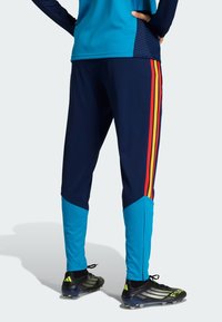 Ναυτικά αθλητικά παντελόνια με μπλε πλευρικά πάνελ και ρίγες κόκκινου-κίτρινου, με κωνικό σχεδιασμό και ύφασμα που απορροφά την υγρασία.