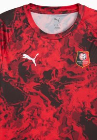 Punane ja must lühikeste varrukatega spordijerseys, millel on geomeetriline muster, niiskust hülgav kangas ja logo rinnal.