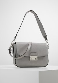 Šedá kabelka z umělé kůže s klopou, stříbrným zapínáním a tenkým nastavitelným popruhem. Vyznačuje se hladkou texturou a minimalistickým designem s černými akcenty.
