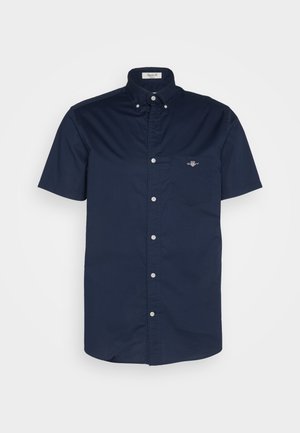 Marineblaues kurzärmeliges Hemd aus Baumwollstoff mit einer Tasche und kleinem Logo sowie einem Kentkragen mit Knopfverschlüssen.