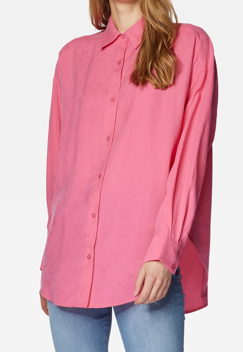 Camicia button-up rosa realizzata in tessuto leggero, con maniche lunghe, colletto classico e vestibilità ampia. Dettagli dei bottoni visibili.