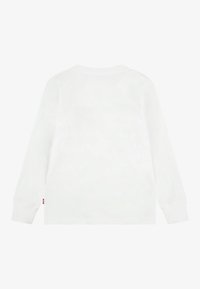 Tricou alb cu mânecă lungă, decolteu rotund și mâneci cu manșete. Prezintă o mică etichetă pe partea stângă jos. Material neted, din bumbac.