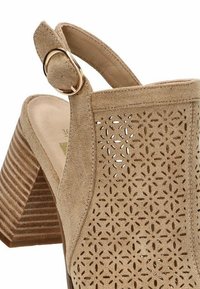 Sandalia de tacón de ante beige con patrón floral recortado, correa ajustable trasera y tacón apilado texturizado.