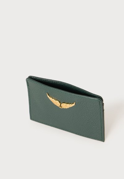 Porte-cartes en cuir texturé vert foncé avec emblème métallique doré en forme d'aile à l'avant, présenté en angle sur une surface blanche.