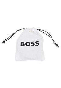 Λευκή βαμβακερή τσάντα με κορδόνι, που φέρει τη λέξη "BOSS" με έντονα μαύρα γράμματα. Υφ ή επιφάνειας με μαύρα κορδόνια για κλείσιμο.