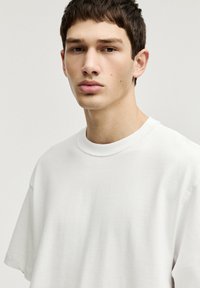 Tricou alb din bumbac, cu mâneci scurte, guler rotund și o croială lejera. Textură netedă și design minimalist. Fără modele sau accente vizibile.