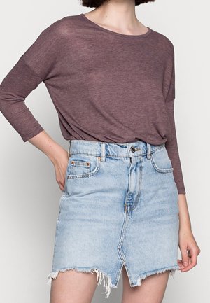Bordeauxrode top met lange mouwen gecombineerd met een lichtblauwe denim rok met een onafgewerkte zoom, knoopsluiting en een frontale split. Zachte, lichte stof.