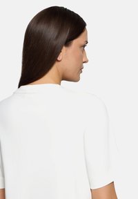 Hvid kortærmet skjorte med afslappet pasform; har en rund udskæring og glat stof, vist fra bagsiden.