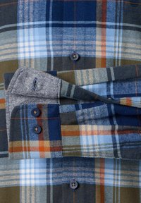 Blau-grünes Karohemd mit einer Mischung aus Karomustern, blauen Knöpfen und kontrastierendem Stoff an den Manschetten, der Textur und Detail verleiht.