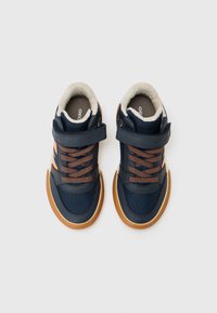 Granatowe sneakersy z teksturowaną cholewką, pomarańczowymi detalami przy sznurówkach, rzepem oraz brązową gumową podeszwą. Futerko wyściełające wokół kostki.