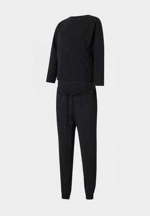 Completo pigiama nero composto da una maglietta a maniche lunghe e pantaloni con cordoncino, realizzato in tessuto morbido con una vestibilità comoda e polsini alla caviglia a punta.