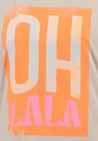T-shirt beige à manches courtes avec un design de texte audacieux. "OH" en argent métallique, "LA LA" en rose vif, sur un fond orange avec une finition texturée.