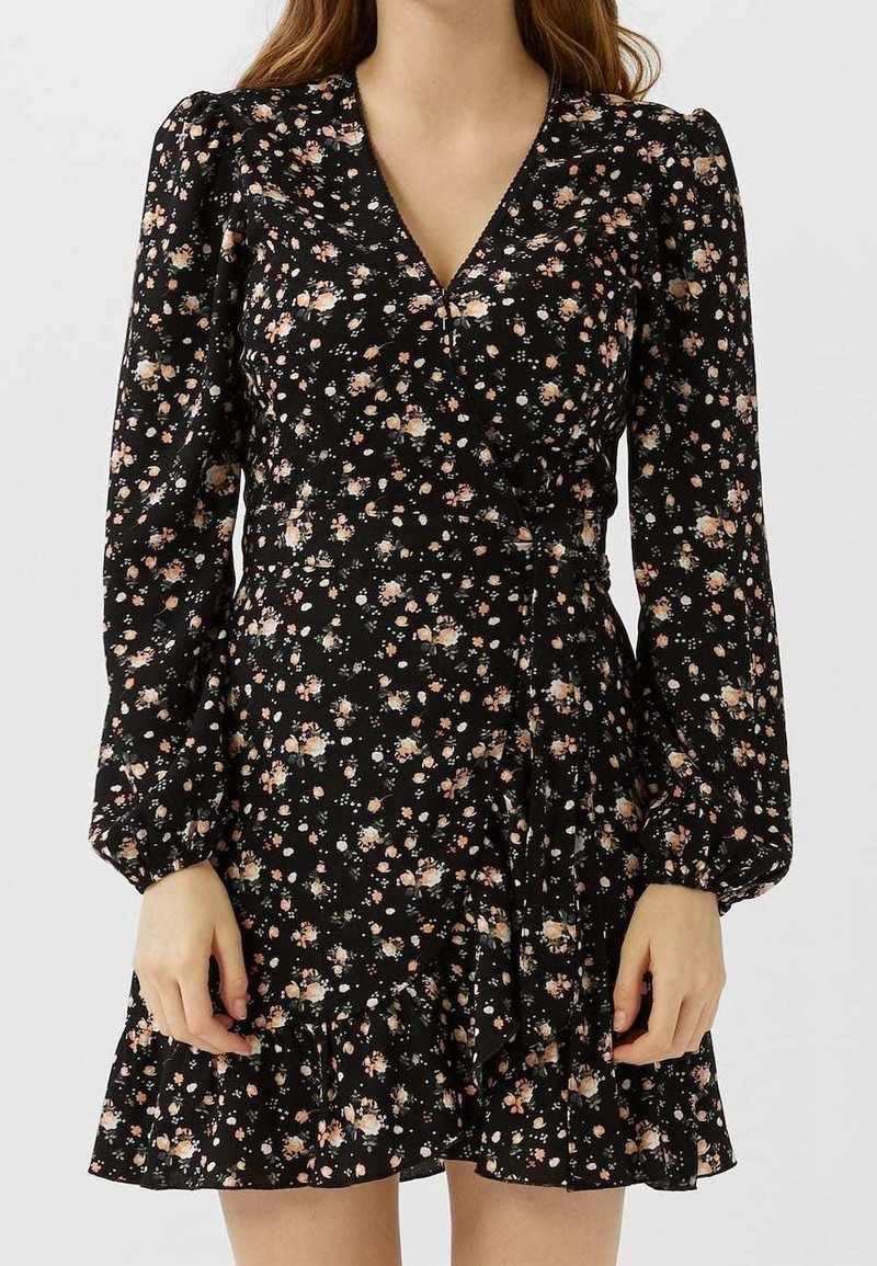 Zwarte bloemenjurk met lange puffmouwen, wikkelontwerp, geribbelde zoom en kleine roze en witte bloemen op een donkere achtergrond.