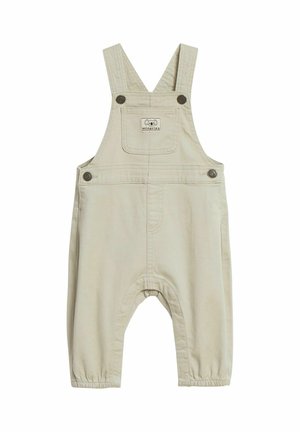 Beige Kinderlatzhose mit verstellbaren Schultergurten, vorderer Brusttasche mit kleinem "minories"-Logo-Patch und Druckknöpfen.