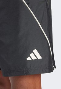Sorte atletiske shorts lavet af letvægtsstof, med en hvid sidestribe og et fremtrædende hvidt Adidas-logo på den nederste kant.