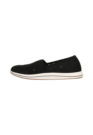 Chaussure slip-on noire perforée avec un dessus texturé, semelle blanche et bandes subtiles le long du bord. Conception légère et respirante.