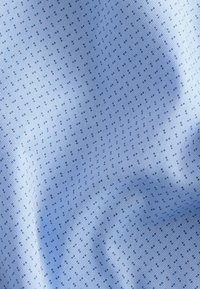 Tessuto blu chiaro con un motivo texturizzato di piccoli puntini e righe, che creano un sottile contrasto visivo nella trama.