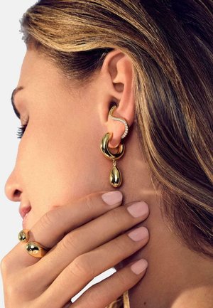 Guldtonade örhängen med en böjd design, en droppformad detalj och rhinestones, som matchas med en ring.