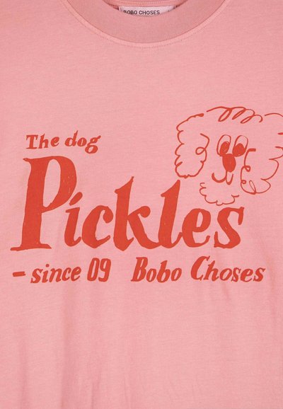 Ružová košeľa s červeným textom "Pes Pickles - od 09 Bobo Choses" a jednoduchým čiarovým kreslením psieho tváre na pravej strane.