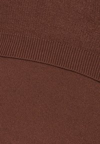 Brun stickad tyg med en ribbad struktur högst upp och en slät yta nedanför, i en enhetlig färg utan synliga mönster.