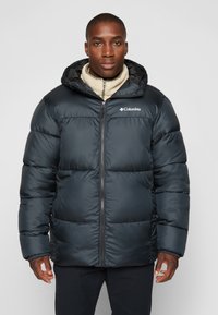 Chaqueta acolchada negra con cremallera frontal y capucha, que cuenta con un diseño acolchado, un forro interior suave y el logo de Columbia en el lado izquierdo del pecho.