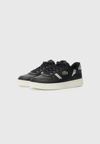 Sneaker in pelle nera con suola in gomma, caratterizzate da una striscia bianca e un logo di coccodrillo verde sul lato. Design con lacci.