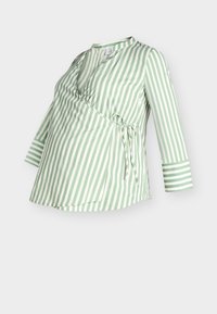 Πράσινη και λευκή ριγέ μπλούζα εγκυμοσύνης με σχέδιο τύπου wrap, μακριά μανίκια και λεπτομέρεια με κορδέλα στη μέση. Κατασκευασμένη από ελαφρύ ύφασμα.