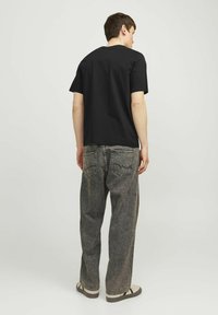 Zwarte katoenen t-shirt met korte mouwen, gecombineerd met losse, vervaagde grijze denim jeans met achterzakken en een recht model.
