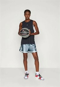 Musta hihaton topi, hopeanväriset satiinishortsit ja punaisilla yksityiskohdilla varustetut koripallokengät. Pitää kädessään mustaa ja hopeaa koripalloa.