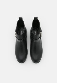 Bottines noires en cuir lisse avec une bande en relief croco brillant, dotées d'une fermeture éclair sur le côté et d'un petit talon carré.
