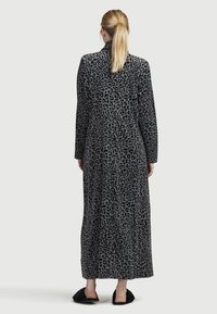 Lång grå kappa med ett svart leopardsmönster, med hög krage och långa ärmar. Mjuk textur och golvlång design.