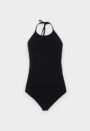 Maillot de bain une-pièce noir avec lien à nouer autour du cou et jambe haute découpée sur un fond clair uni.