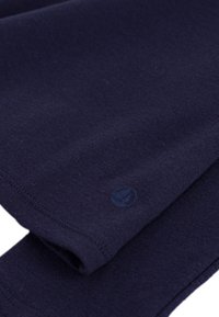 Dunkelblauer Baumwollstoff mit glatter Textur, der ein dezentes Logo-Druckmotiv und genähte Saumdetails auf einer Seite aufweist.