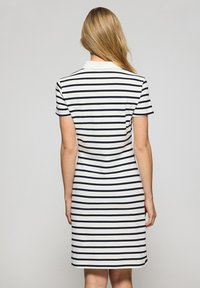 Kurzärmeliges Kleid mit horizontalen navy- und weißen Streifen, einem Kragen und einer figurnahen Silhouette, die bis zur Mitte des Oberschenkels reicht.
