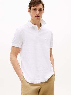 Polo blanc à manches courtes, en coton, avec une patte de boutonnage à trois boutons et un petit logo sur la poitrine gauche.
