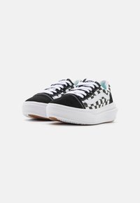 Baskets basses à carreaux noir et blanc avec une semelle blanche, tige en daim et lacets contrastés. Présente le logo de la marque sur la languette.