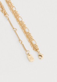 Colar em tom dourado com várias camadas, apresentando diferentes estilos de correntes, incluindo elos redondos e uma pequena placa com "RL", terminado com fecho de lagosta.