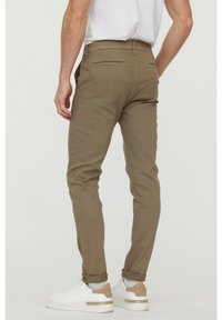 Kaki slim-fit byxor med strukturerad tyg, som har bakfickor och en medelhög midja, i kombination med vita sneakers.