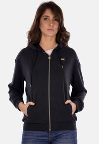 Felpa nera con zip, cappuccio, tasche frontali e dettagli dorati. Realizzata in tessuto morbido, presenta una vestibilità comoda e polsini a coste.