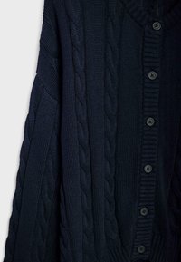 Ciemnoniebieski, dziergany sweter z wzorem warkocza, prążkowanymi krawędziami i sześcioma guzikami z przodu. Miękka faktura, długie rękawy.