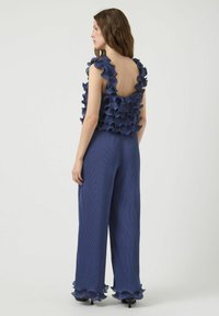 Marineblauwe jumpsuit met ruches op de schouders en de rug, geweven stof, wijde broekspijpen en ruches aan de mouwen.
