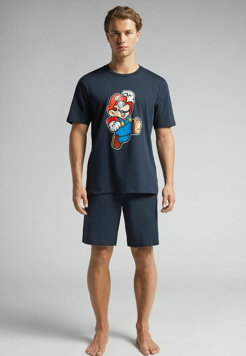 Navy Baumwoll-Pyjama-Set mit einem kurzärmligen T-Shirt mit einem bunten Mario-Graphic, kombiniert mit passenden Shorts. Weiche Struktur, lässige Passform.