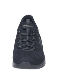 Schwarze Sportschuhe mit Obermaterial aus Strickgewebe, schnürsenkelfreiem Design, strukturiertem Oberflächen und Gummisohle, die ein dezentes Logo an der Seite aufweist.