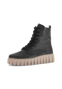Black leather high-top boot with thick beige ridged sole and black laces, shown in side profile on white background.