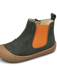 Bottine en suede verte avec un panneau élastique orange, semelle en caoutchouc brun texturé et accents de couture minimalistes. Conçue pour le confort et la facilité.